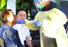 A medical worker does a mouth swab on President Rodrigo Duterte Thursday as close ally Sen. Christopher “Bong” Go looks on. PTV