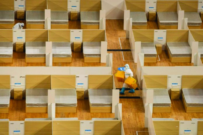 A staff member removes waste after the final patients were discharged from a temporary hospital set up to treat people with the COVID-19 coronavirus in a sports stadium in Wuhan, China. AFP