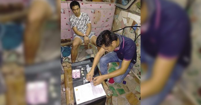 An antidrug officer inspects items seized from Mark Lawrence Onggada, who was nabbed in a buy-bust operation in Barangay 3, Bacolod City on March 19. POLICE STATION 2/ BCPO