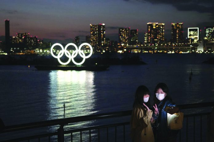 Two women take a selfie with the Olympic rings in the background in the Odaiba section of Tokyo, Thursday, March 12, 2020. AP