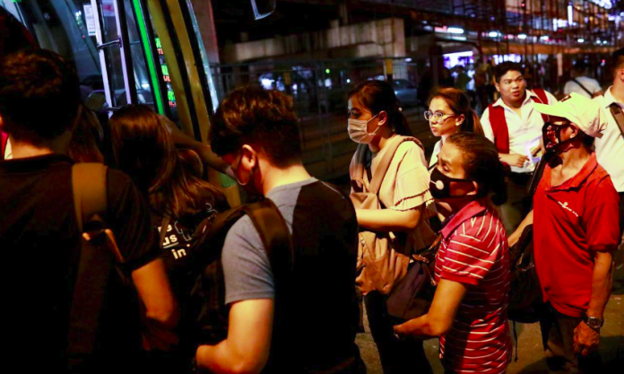 People wearing protective masks, following an outbreak of coronavirus disease, rush to get in a bus in Manila, Mar. 12, 2020. REUTERS