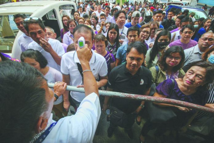 Security personnel check the body temperature of all Manila City Hall employees and visitors before entering the vicinity on Monday, amid confirmation of novel coronavirus cases in the country. The health department confirmed 10 cases of COVID-19 as of Monday and urged the public to avoid crowded places and attending mass gatherings in an attempt to prevent spread of the coronavirus. ABS-CBN NEWS