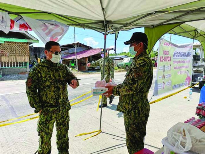 Western Visayas police director Brigadier General Rene Pamuspusan (left) gives boxes of face masks and fruits to Dumarao chief of police Larnel Frial, which are to be used by personnel who conduct checkpoint at the border of Iloilo and Capiz provinces in Barangay Aglalana, Dumarao, Capiz on March 23. PIA