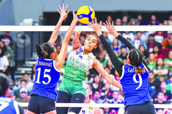 Ilongga Aduke Ogunsanya of the De La Salle University Lady Spikers attempts to score past two Ateneo defenders. UAAP