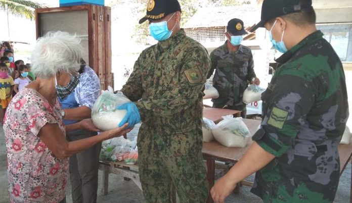 An old woman receives a food pack from policemen of the Iloilo Police Provincial Office. “We hope this humble support can help ease the burden of poor families who are the most badly affected by the enhanced community quarantine,” says Police Colonel Paul Kenneth Lucas, Iloilo police director. IPPO PHOTO