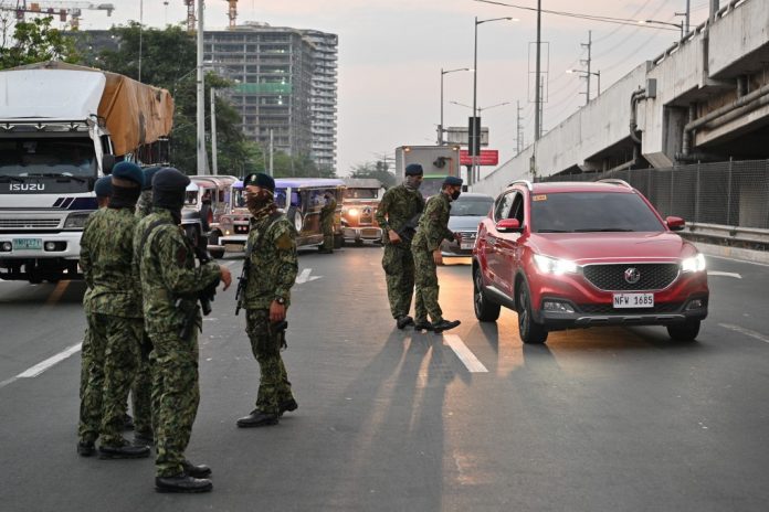 Philippine police personnel man a checkpoint bordering nearby Cavite province and suburban Las Pinas in Manila on March 15, 2020, as the government steps up efforts to curb the spread of the new coronavirus. AFP