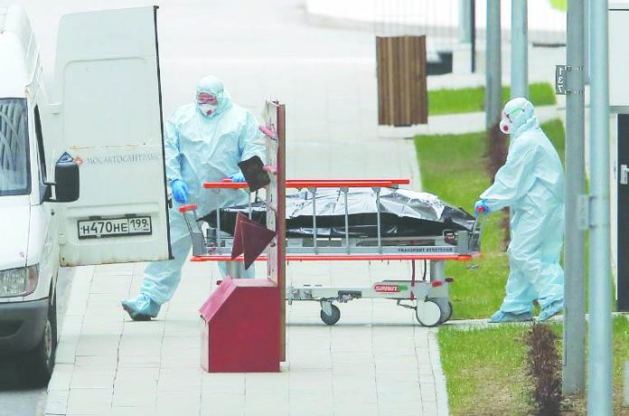 Medical specialists wearing protective gear push a stretcher towards an ambulance while relocating a non-transparent bag outside a hospital for patients infected with the coronavirus disease on the outskirts of Moscow, Russia April 20, 2020. REUTERS