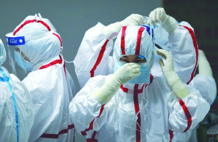 Medical staff put on protective equipment before attending to COVID-19 patients at the Red Cross Hospital in Wuhan in China's central Hubei province on March 16, 2020. AFP