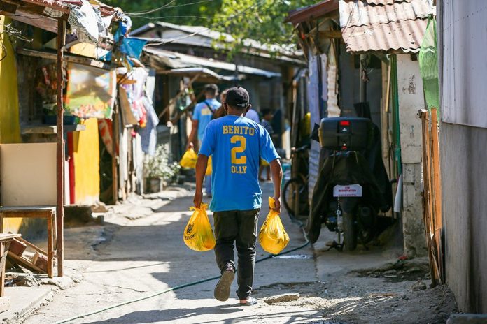 People from the local barangay bring food relief packs to residents of Brgy. San Miguel in Pasig City on Thursday. ABS-CBN