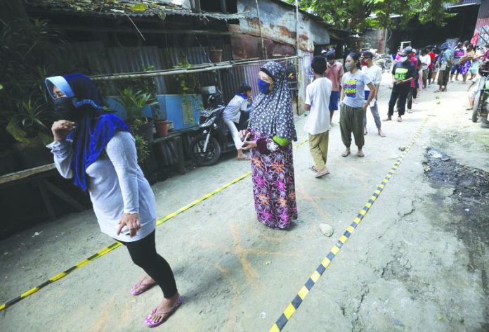 Residents practice social distancing as they queue for donated food during the coronavirus pandemic in a slum area in Jakarta, Indonesia, Wednesday, April 22, 2020. AP