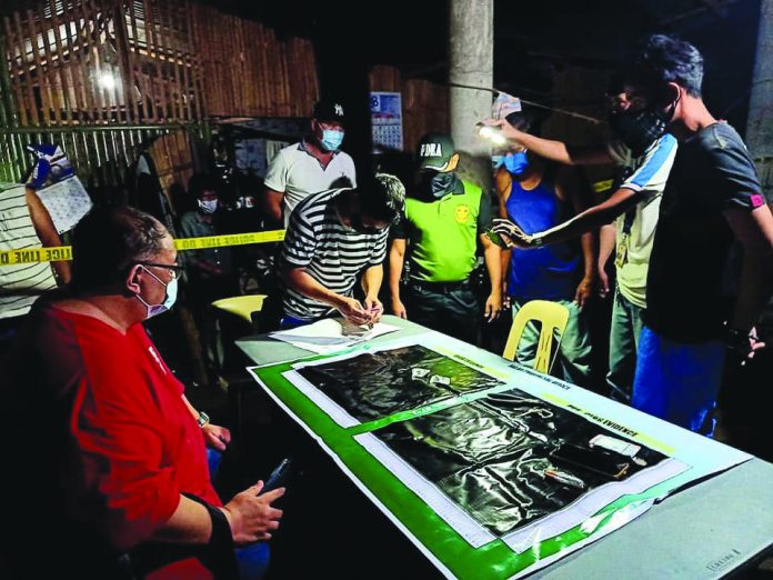 Drug suspect John Lee Yapendon (right) stands handcuffed while antidrug operatives conduct an inventory of items seized from him during an entrapment operation in Barangay Navitas, Numancia, Aklan on July 18. PDEA REGIONAL OFFICE VI FB