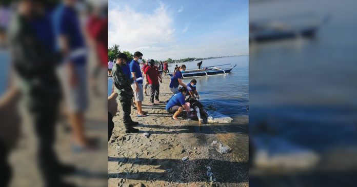 Personnel of Bacolod and Talisay Disaster Risk Reduction Management offices bring the body of Carl Gabriel Cabrillo ashore in Talisay City, Negros Occidental on July 17. TALISAY CITY POLICE STATION