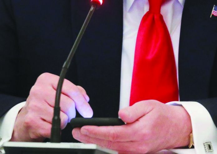 United States President Donald Trump taps the screen on a mobile phone at the approximate time a tweet was released from his Twitter account, during a roundtable discussion at the White House in Washington on June 18, 2020. REUTERS/LEAH MILLIS/FILE PHOTO