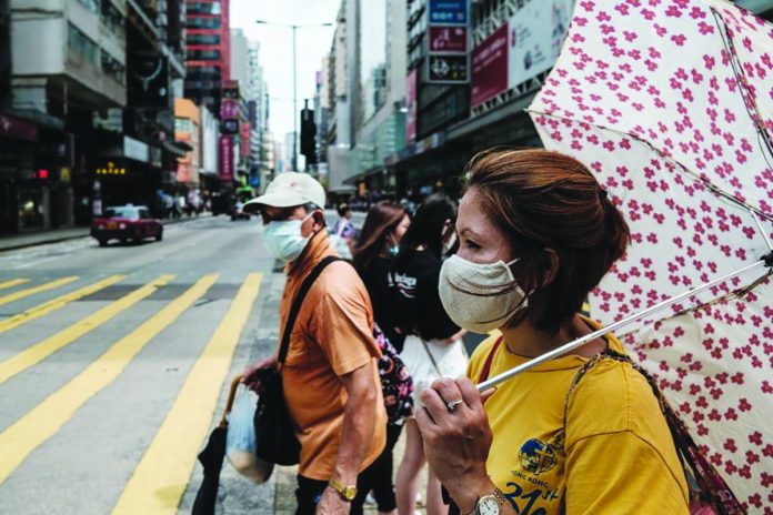 Pedestrians prepare to walk across a main road in Hong Kong on July 20, 2020. AFP