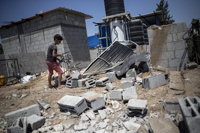 A Palestinian boy inspects the damage in his family home following Israeli airstrikes in Buriej refugee camp, central Gaza Strip, Saturday, Aug. 15, 2020. AP PHOTO/KHALIL HAMRA