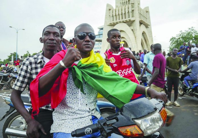 A man wears a national flag as he celebrates with others in the streets in Mali’s capital Bamako on August 18, 2020. Mutinous soldiers detained Mali’s president and prime minister Tuesday after surrounding a residence and firing into the air in an apparent coup attempt after several months of demonstrations calling for President Ibrahim Boubacar Keita’s ouster. AP