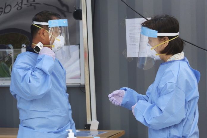 A medical worker measures his own body temperature during the COVID-19 testing at a makeshift clinic in Seoul, South Korea on Aug. 26, 2020. AP