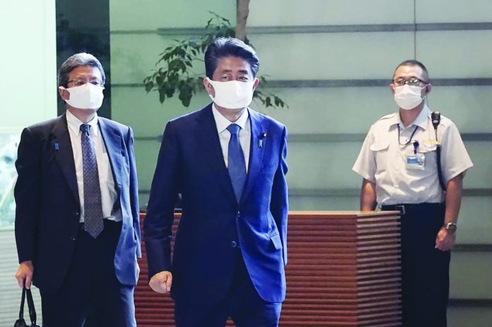 Japan's Prime Minister Shinzo Abe (center) walks at prime minister's office in Tokyo Friday, Aug. 28, 2020. AP