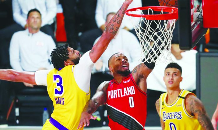 Los Angeles Lakers forward Anthony Davis (3) blocks a shot by Portland Trail Blazers guard Damian Lillard (0) as Lakers forward Kyle Kuzma (0) looks on during the first half of Game 2 of an NBA basketball first-round playoff series, Thursday, in Lake Buena Vista, Florida. AP