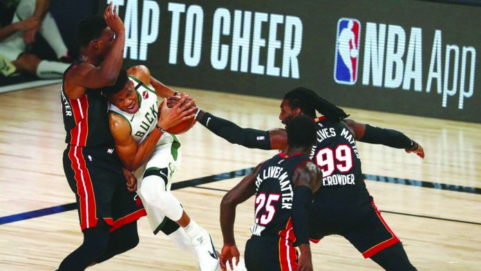 Milwaukee Bucks’ Giannis Antetokounmpo works his way past Miami Heat’s Bam Adebayo as Jae Crowder tries to help and Kendrick Nunn looks on. AP