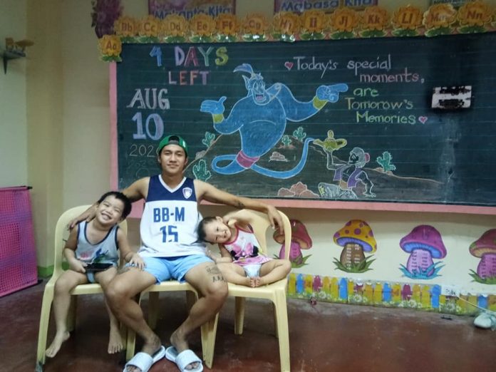 Mitchelle “Bon” Silaya holds classes to his children Alfonzo and Brianna inside their quarantine facility at a public elementary school in Bago City, Negros Occidental on Aug. 10. BON SILAYA