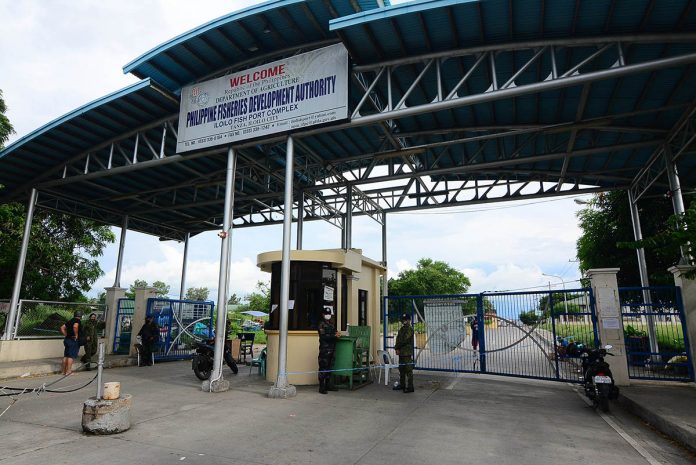 Policemen are posted at the entrance of the Iloilo Fishing Port Complex in Barangay Tanza, Iloilo City on Wednesday. Mayor Jerry Treñas extended the facility’s lockdown for another 72 hours after 26 more individuals got infected with coronavirus. IAN PAUL CORDERO/PN