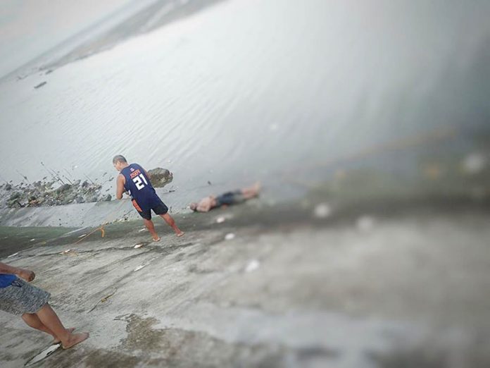 Residents fish out the body 53-year-old pedicab driver Avelino Alisbo off the waters of Barangay Singcang-Airport in Bacolod City on Thursday morning. Officers of Police Station 8 did not find any wounds on Alisbo’s body suggestive of murder. BCPO