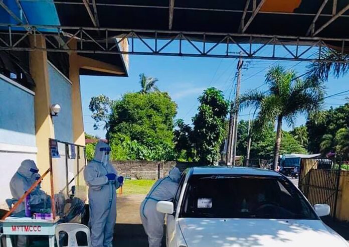 A motorist gets tested for coronavirus disease 2019 at a drive-through at the ABAP gym in Bago City, Negros Occidental. Glenly Casona, swab team leader and medical technologist of the City Health Office, says the target individuals will be swabbed inside their own vehicles. BAGO CITY PIO