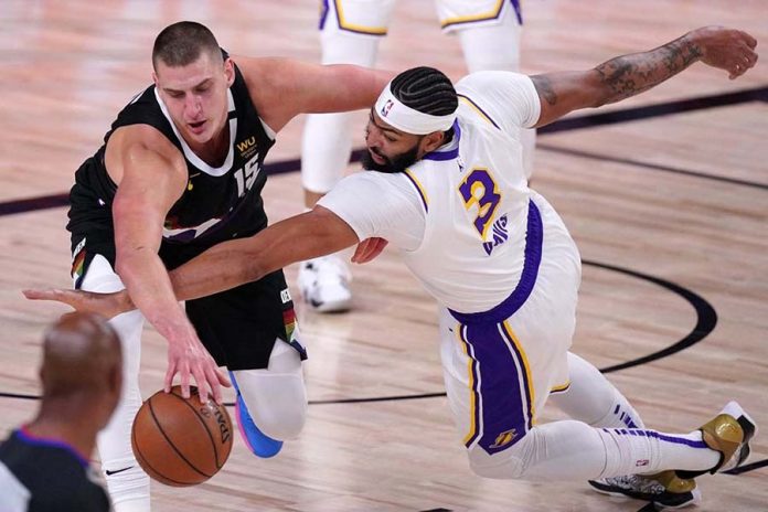 Denver Nuggets center Nikola Jokić (left) and Lakers forward Anthony Davis battle for a loose ball during the first half of Game 3. MARK J. TERRILL / ASSOCIATED PRESS