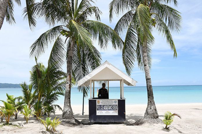 A policeman standing guard along the empty famous white beach of Boracay Island in Malay, Aklan. Tourists from areas under general community quarantine may enjoy what the famed-island resort offers starting next month, says Tourism secretary Bernadette Puyat. ERNESTO CRUZ/AFP