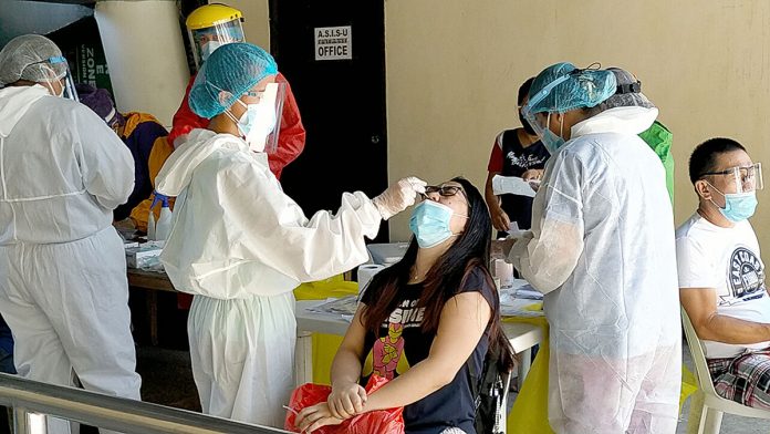 Health workers wearing protective gear extract nasal swab samples from a city government employee during the first day of mass testing at the Iloilo City Freedom Grandstand on Wednesday, Sept. 23. Panay News