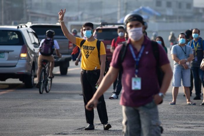 Workers wearing face masks wait for their ride along a road in Quezon City, Metro Manila on May 18, 2020. ELOISA LOPEZ/REUTERS