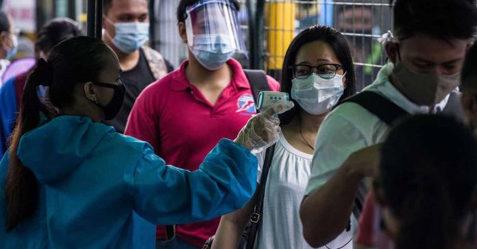 A passenger has her body temperature taken before boarding a bus in Manila on July 7, 2020. AFP