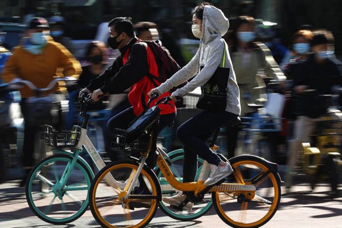 People wearing face masks to help curb the spread of the coronavirus ride bicycle during the morning rush hour in Beijing on Oct. 12. ANDY WONG/AP PHOTO