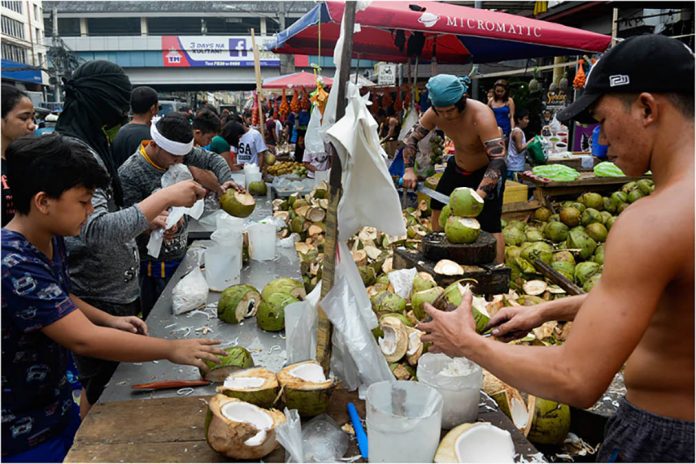 Workers crack open coconuts at a public market near Taft Avenue in Pasay City. GEORGE CALVELO/ABS CBN NEWS