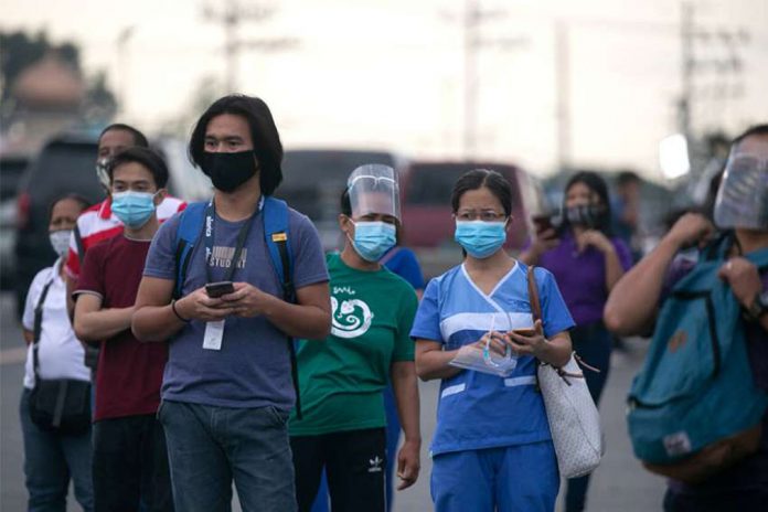 Workers wearing protective masks wait for shuttle services in Manila, Philippines. According to the Department of Labor and Employment, all employers are required to release their workers’ 13th month pay on or before Dec. 24. CNS PHOTO/ELOISA LOPEZ, REUTERS