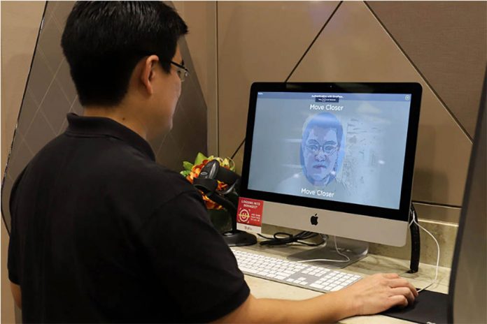 A staff member of government technology agency demonstrates the use of facial verification technology to access government services on a computer at a community center in Singapore. MARTIN ABBUGAO/AFP