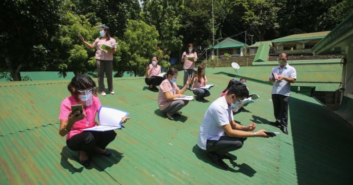 Teachers at a secondary school in Batangas City climb on the roof to access a better internet connection as they monitor their students’ activities during the school year’s opening on Monday, Oct. 5, 2020. PHOTO VIA ABS-CBN NEWS