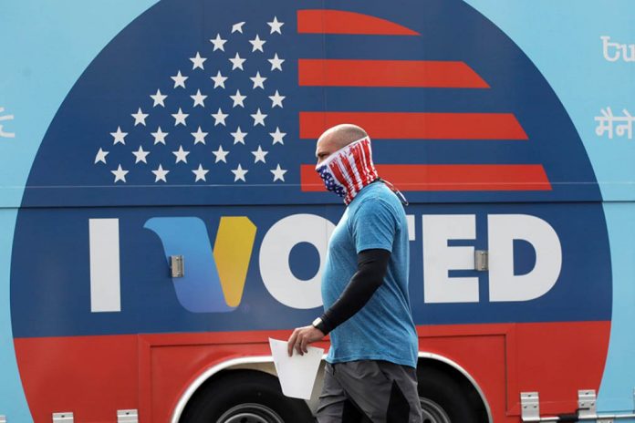 A man wears a mask as he walks past an “I voted” sign in Santa Clarita, California on May 12, 2020. MARCIO JOSE SANCHEZ/AP