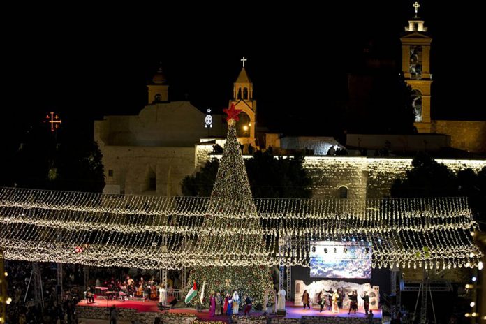 Palestinian Christians celebrate the lighting of a Christmas tree outside the Church of the Nativity, traditionally believed by Christians to be the birthplace of Jesus Christ in the West Bank city of Bethlehem. MAJDI MOHAMMED/AP PHOTO