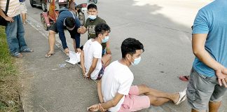 The 24-year-old Juno Samontanes and 19-year-old-old AJ Mar Pari-an sit handcuffed while antidrug operatives inspect sachets of suspected shabu during a buy-bust operation in Barangay Tagbak, Jaro, Iloilo City on Dec. 13. IAN PAUL CORDERO/PN