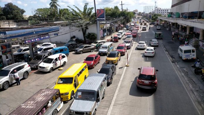 HEAVY TRAFFIC. Vehicles are “bumper to bumper” and slow on Luna Street, La Paz, Iloilo City yesterday. The 50 percent price cut at Petron’s select branches saw motorists flock pump stations all over the metro. IAN PAUL CORDERO/PN