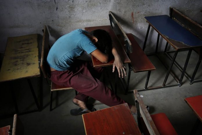 A bonded child laborer rests on a school desk in a safe house after being rescued during a raid by workers from Save Childhood Movement at a garments factory in New Delhi, India. KEVIN FRAYER /AP PHOTO