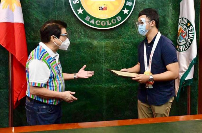 Mayor Evelio Leonardia (left) of Bacolod City hands over a framed copy of his executive order to Patrick Joseph Mabugat (right) congratulating the latter for ranking No. 2 in the 2020 Physician Licensure Examination. BACOLOD CITY PIO