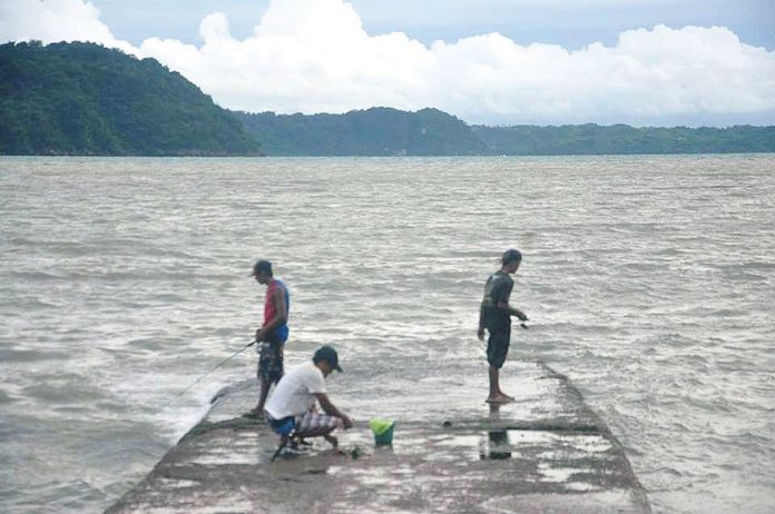 This portion of the breakwater of Fort San Pedro in Iloilo City is the perfect spot for fishing, according to these men. From a distance could be seen the island province of Guimaras. PN PHOTO