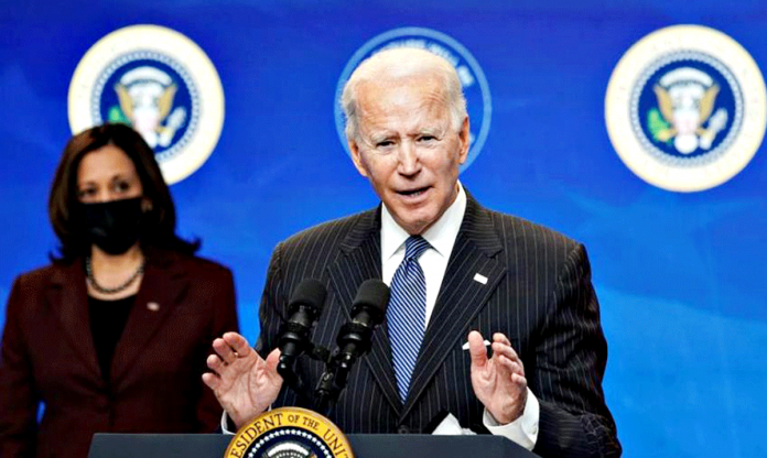 President Joe Biden speaks about administration plans to strengthen American manufacturing as Vice President Kamala Harris listens in the South Court Auditorium at the White House in Washington, U.S., January 25, 2021. REUTERS/Kevin Lamarque