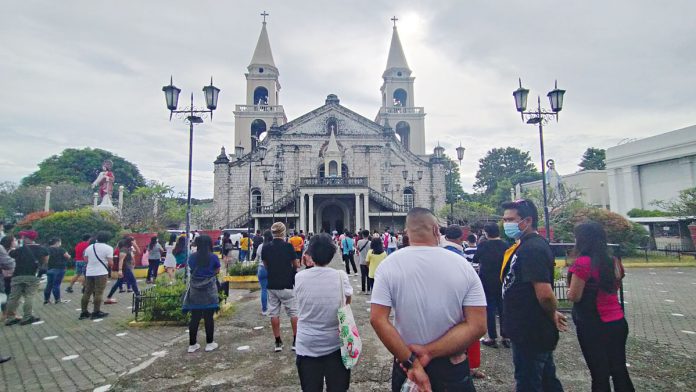 PRAYING FOR HEALING. Parishioners attending 2021’s first Sunday Mass outside the Jaro Metropolitan Cathedral observe physical distancing to avoid spreading the coronavirus disease 2019. People attending the Mass, too, are wearing facemasks and have to undergo a footbath before entering the cathedral. IAN PAUL CORDERO/ PN