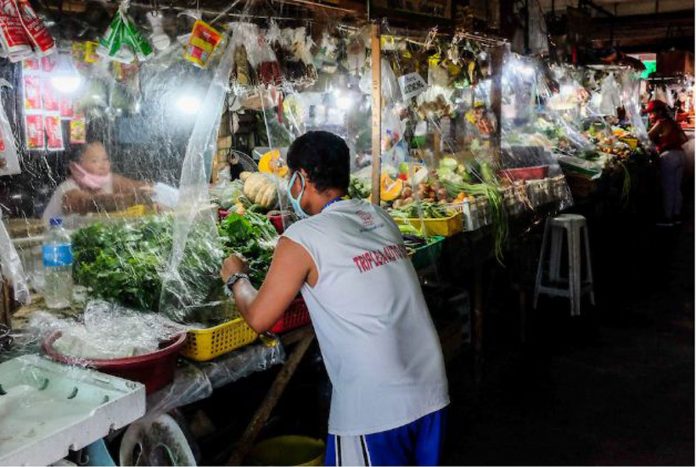 Stall owners install plastic barriers and encourage physical distancing at the Las Piñas City public market on March 31, 2020.  GEORGE CALVELO/ABS-CBN NEWS