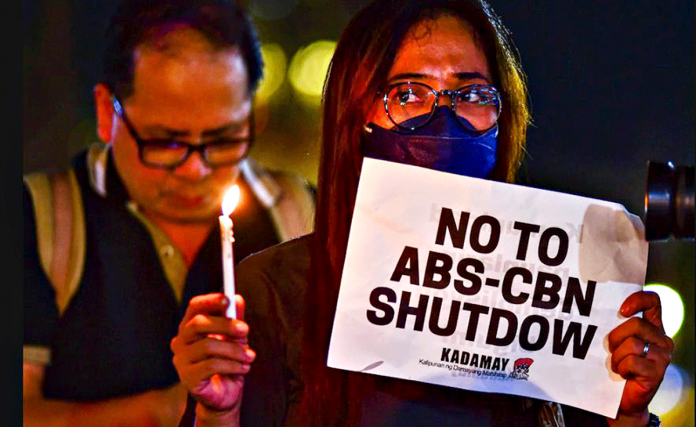 With a lighted candle and a banner which says, “NO TO ABS-CBN SHUTDOWN,” a woman joins the rally of ABS-CBN’s supporters to denounce the cancelation of the network’s franchise on Feb. 10, 2020. MARIA TAN/ABS-CBN NEWS