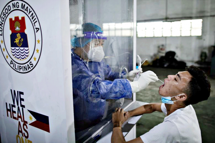 A health worker performs a swab test to a vendor in Tondo, Manila. REUTERS/ELOISA LOPEZ/FILE PHOTO